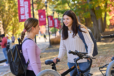 Two girls talking next to bicycles. Links to Gifts of Life Insurance