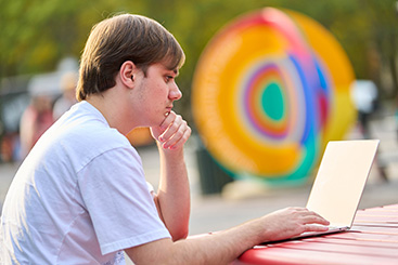 A student looking at their laptop. Links to Gifts That Protect Your Assets